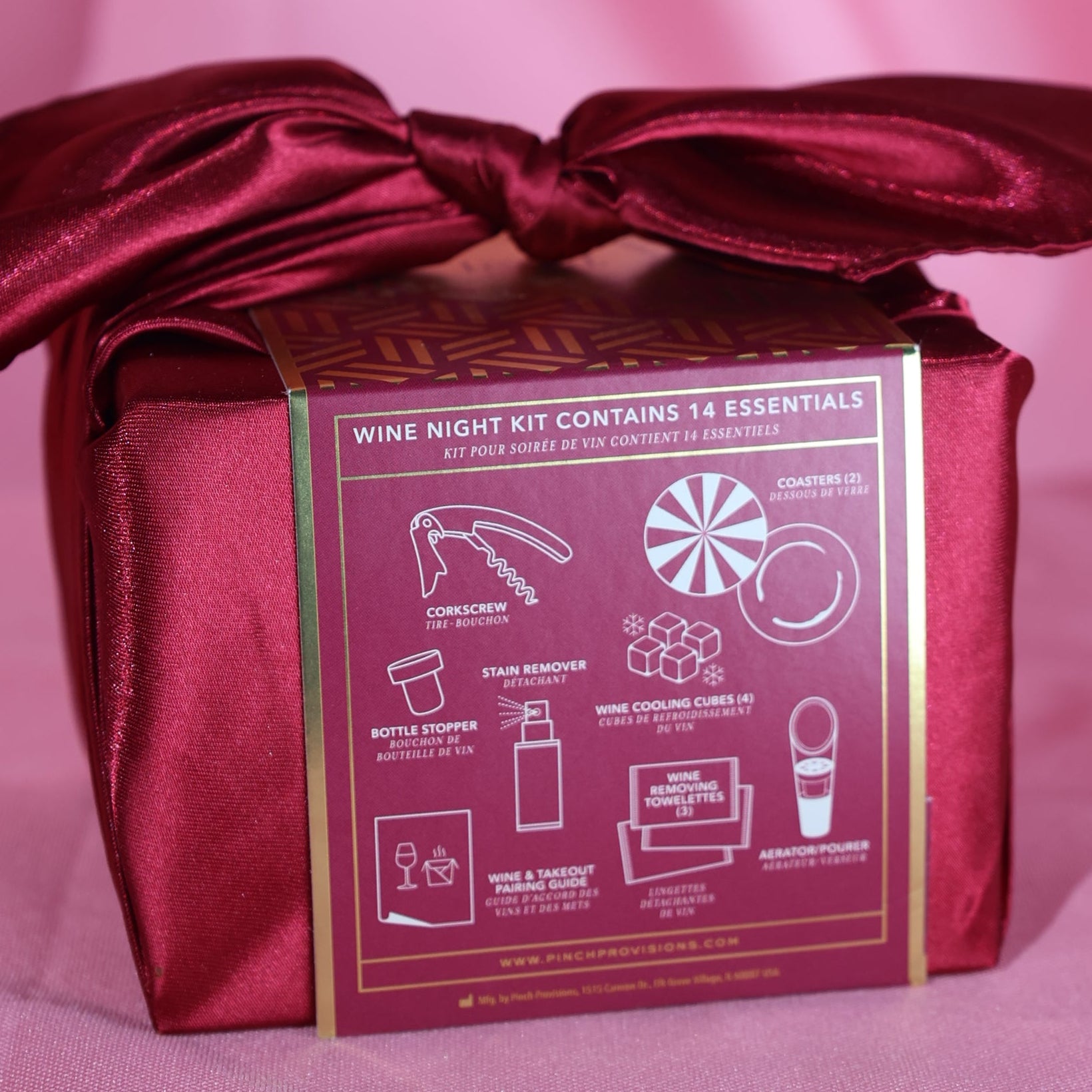 Maroon gift box with a bow on a pink fabric background